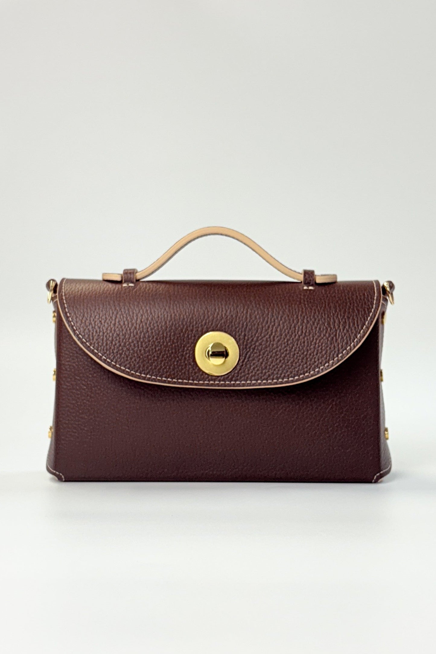 Brown leather handbag with gold clasp on a light gray background