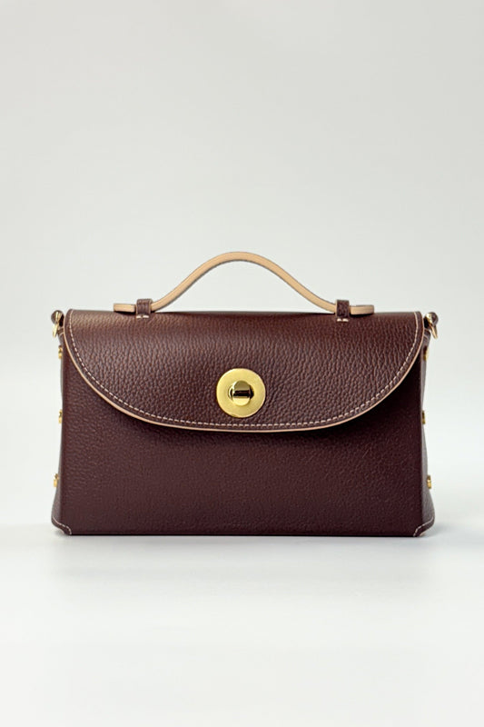 Brown leather handbag with gold clasp on a light gray background