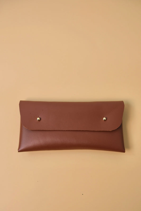 Brown leather pouch with silver studs on a beige background