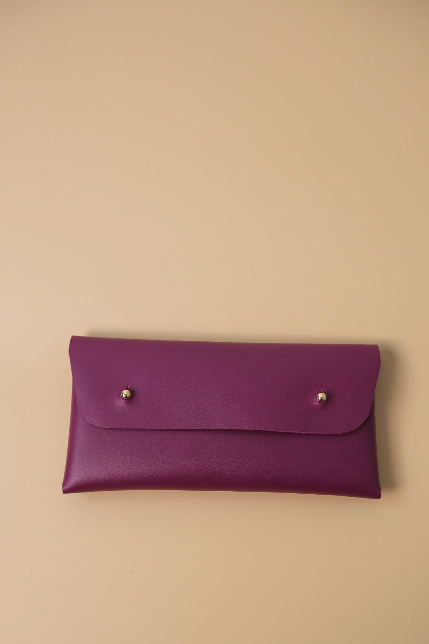 Purple leather clutch on a beige background
