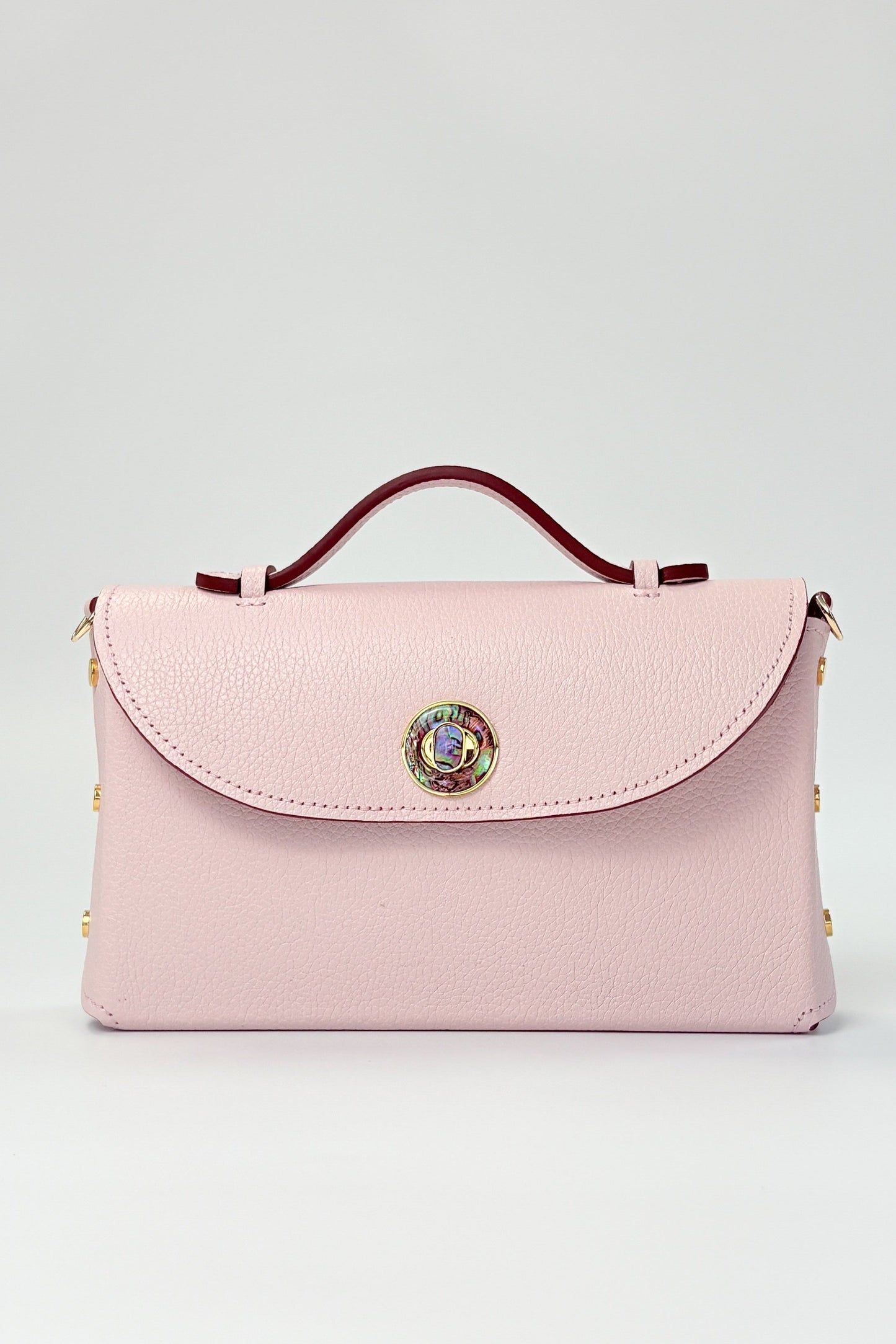 Pink handbag with decorative clasp on a light gray background