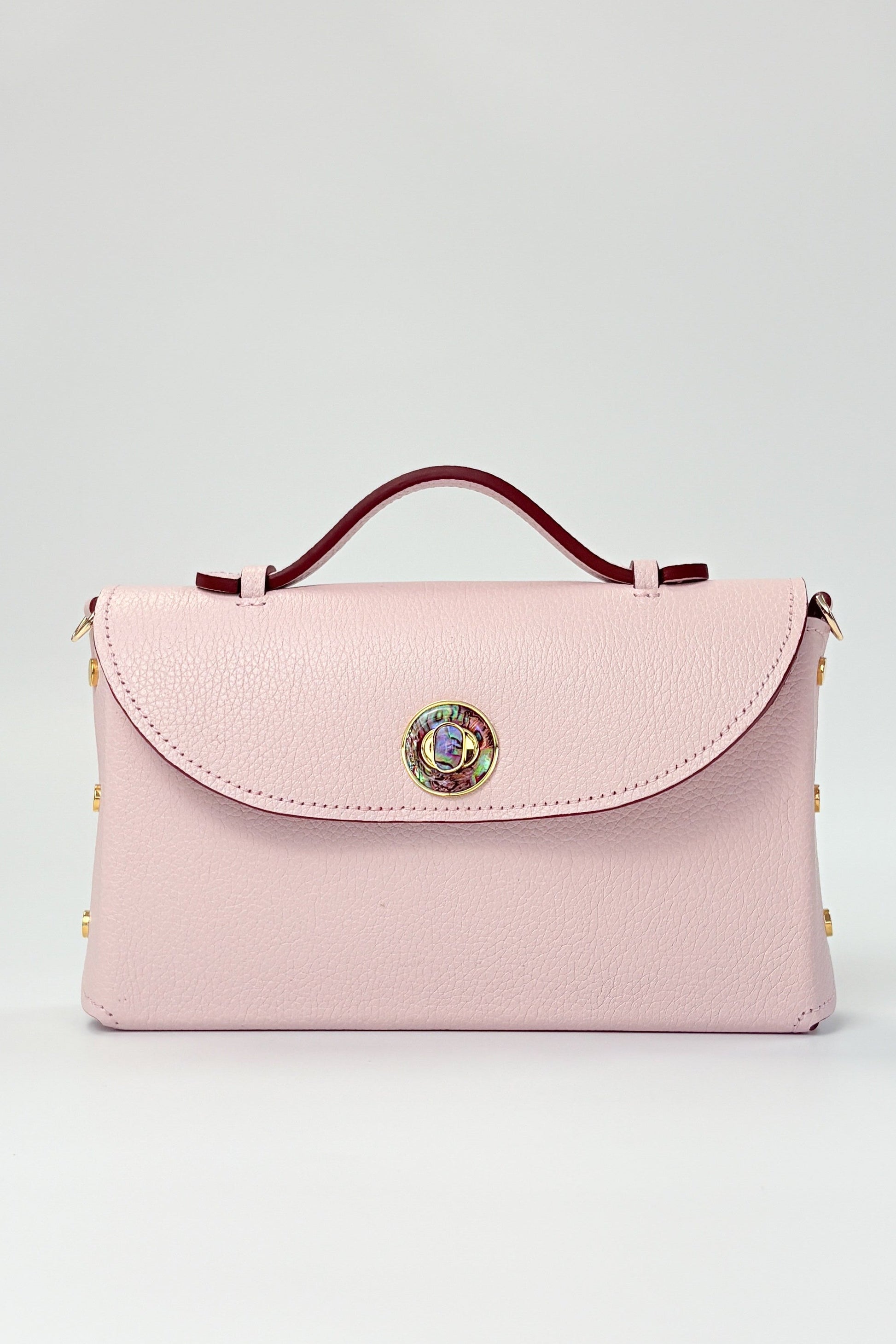 Pink handbag with decorative clasp on a light gray background
