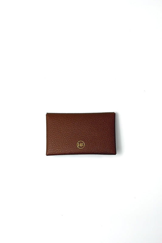 Brown leather cardholder with gold logo on a white background